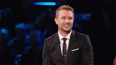 A Man In A Suit And Tie Is Holding A Piece Of Paper GIF