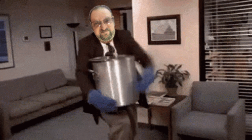 A Man In A Suit And Tie Is Holding A Pot GIF