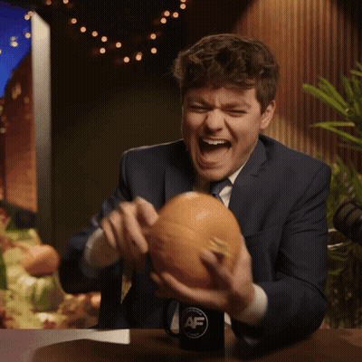 A Man In A Suit And Tie Is Holding A Pumpkin In Front Of A Cup That Says Af GIF