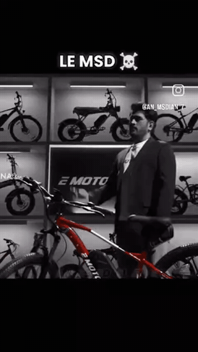 A Man In A Suit And Tie Is Holding A Red Bicycle In Front Of A Wall Of Bikes . GIF