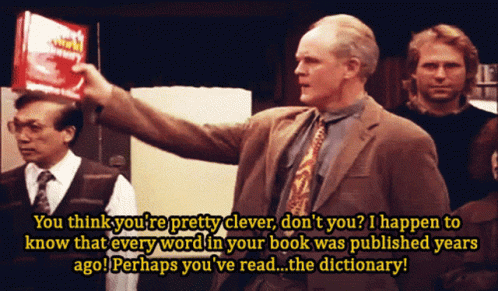 A Man In A Suit And Tie Is Holding A Red Book That Says Dictionary On It GIF