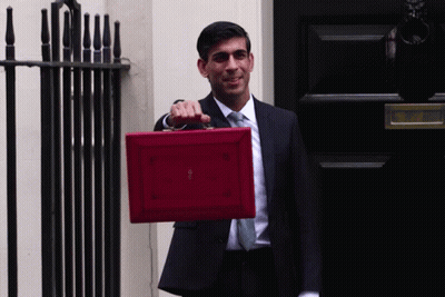 A Man In A Suit And Tie Is Holding A Red Briefcase That Says ' British ' On It GIF