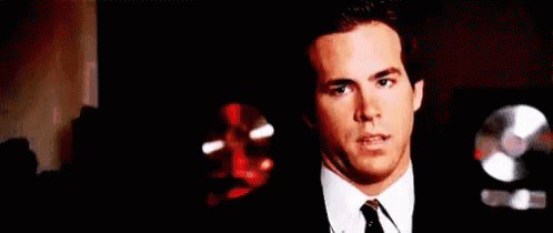 A Man In A Suit And Tie Is Holding A Red Object In His Hands . GIF