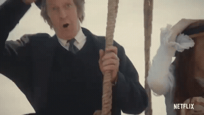 A Man In A Suit And Tie Is Holding A Rope In Front Of A Woman In A White Dress . GIF