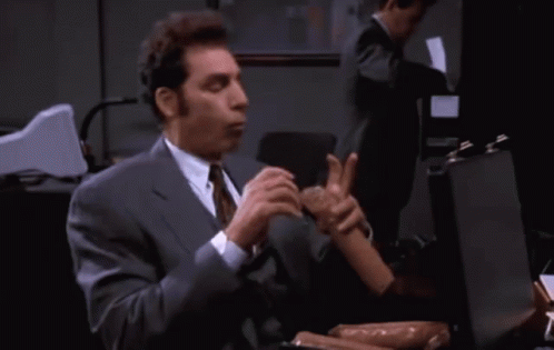 A Man In A Suit And Tie Is Holding A Sausage GIF