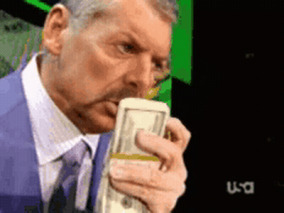 A Man In A Suit And Tie Is Holding A Stack Of Money In Front Of A Tv Screen That Says Usa GIF