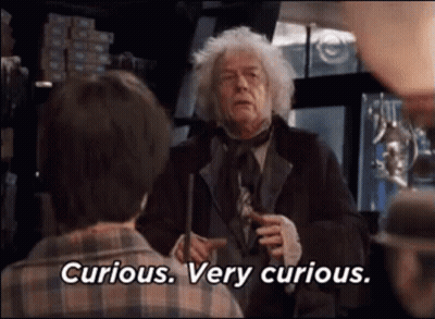 A Man In A Suit And Tie Is Holding A Wand And Talking To A Boy . GIF