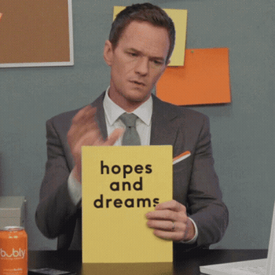 A Man In A Suit And Tie Is Holding A Yellow Sign That Says Hopes And Dreams GIF