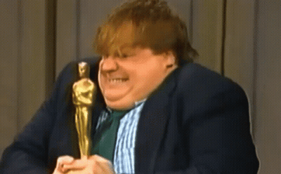 A Man In A Suit And Tie Is Holding An Oscar Statue And Talking Into A Microphone . GIF