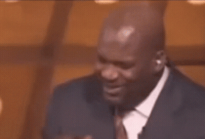 A Man In A Suit And Tie Is Holding His Hand To His Mouth GIF