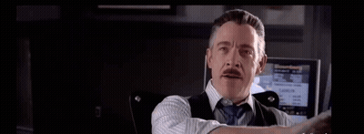 a man in a suit and tie is holding his hand up in front of a screen .