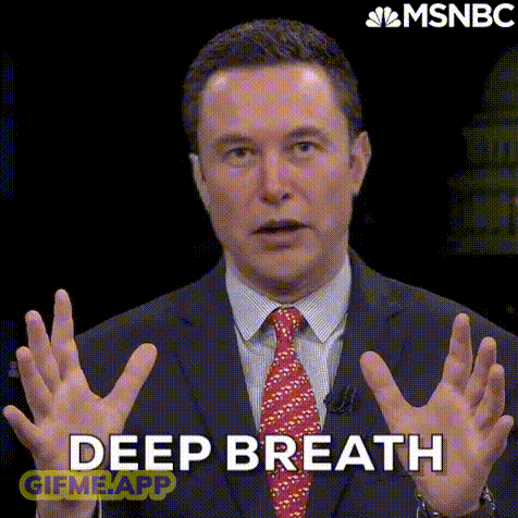 A Man In A Suit And Tie Is Holding His Hands Up And Saying Deep Breath . GIF