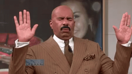 A Man In A Suit And Tie Is Holding His Hands Up In Front Of A Picture Of A Woman . GIF