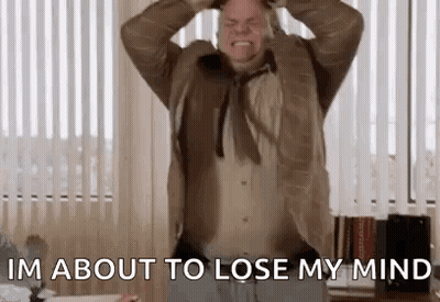 A Man In A Suit And Tie Is Holding His Head While Screaming . GIF
