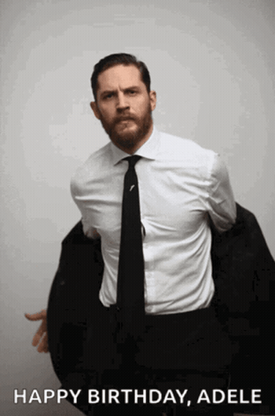 A Man In A Suit And Tie Is Holding His Jacket Over His Shoulder And Says " Happy Birthday Adele " GIF