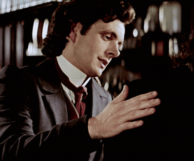 A Man In A Suit And Tie Is Holding Something In His Hands GIF