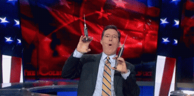 A Man In A Suit And Tie Is Holding Two Syringes In His Hands . GIF