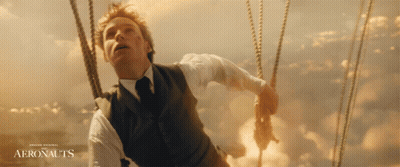 A Man In A Suit And Tie Is In A Hot Air Balloon With The Words Aeronauts On The Bottom GIF