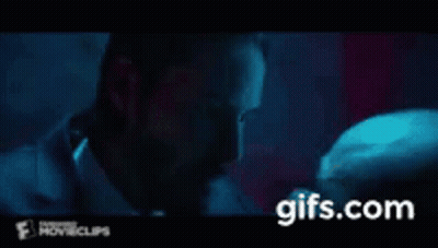 A Man In A Suit And Tie Is Kissing Another Man On The Cheek . GIF