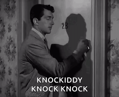A Man In A Suit And Tie Is Knocking On A Door That Says 2B On It GIF