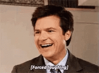 A Man In A Suit And Tie Is Laughing . GIF