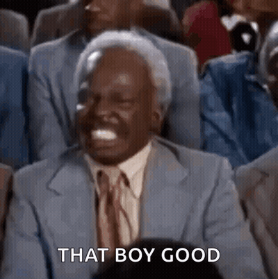 A Man In A Suit And Tie Is Laughing In A Crowd Of People . GIF