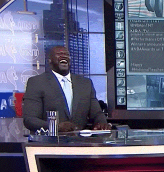 A Man In A Suit And Tie Is Laughing In Front Of A Sign That Says Nba GIF