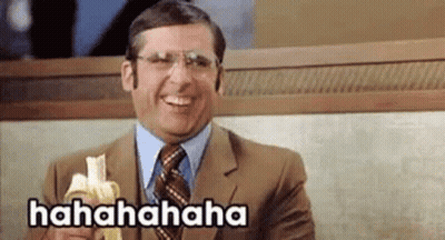 A Man In A Suit And Tie Is Laughing While Holding A Banana . GIF