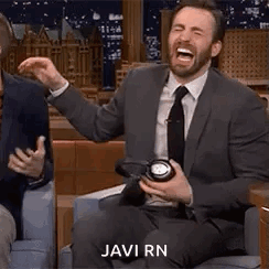 A Man In A Suit And Tie Is Laughing While Holding A Clock In His Hand . GIF