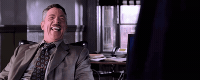 A Man In A Suit And Tie Is Laughing While Sitting In Front Of A Computer . GIF