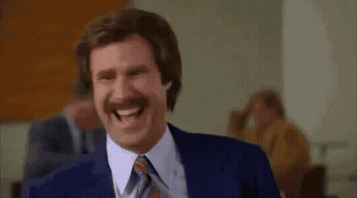 A Man In A Suit And Tie Is Laughing While Standing In Front Of A Group Of People . GIF