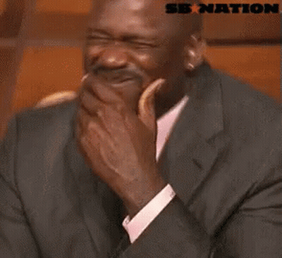 A Man In A Suit And Tie Is Laughing With A Sb Nation Logo Behind Him . GIF