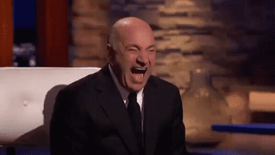 A Man In A Suit And Tie Is Laughing With His Mouth Open . GIF