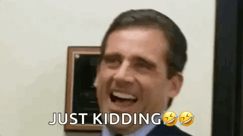 A Man In A Suit And Tie Is Laughing With His Mouth Open And The Words `` Just Kidding '' Next To Him . GIF