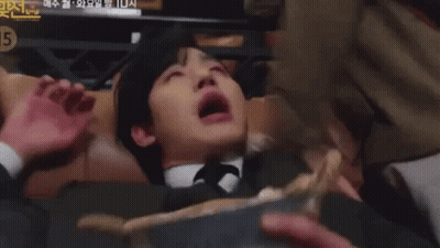 A Man In A Suit And Tie Is Laying On His Back With His Mouth Open . GIF