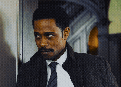 A Man In A Suit And Tie Is Leaning Against A Door GIF