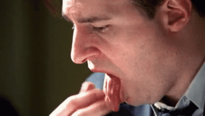 A Man In A Suit And Tie Is Licking His Hand . GIF