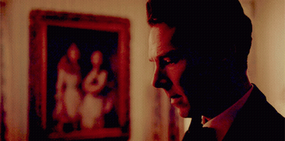 A Man In A Suit And Tie Is Looking At A Framed Picture GIF