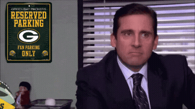 A Man In A Suit And Tie Is Looking At A Green Bay Packers Reserved Parking Sign GIF