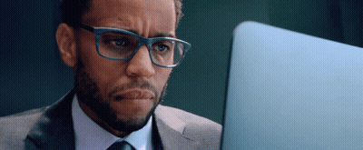 A Man In A Suit And Tie Is Looking At A Laptop GIF
