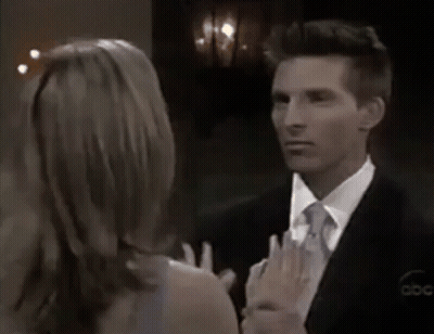 A Man In A Suit And Tie Is Looking At A Woman In A Dress GIF