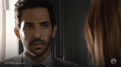 A Man In A Suit And Tie Is Looking At A Woman With The Blacklist Written On The Bottom GIF