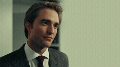 A Man In A Suit And Tie Is Looking At Something GIF
