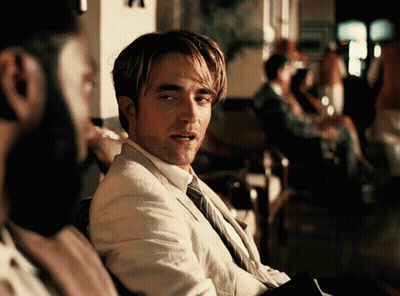 A Man In A Suit And Tie Is Looking At Something GIF