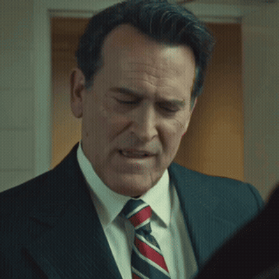 A Man In A Suit And Tie Is Looking At Something GIF