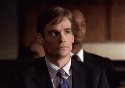 A Man In A Suit And Tie Is Looking At Something GIF