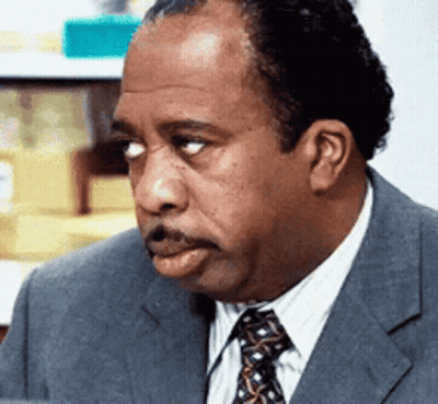 A Man In A Suit And Tie Is Looking At Something GIF