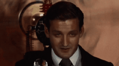 A Man In A Suit And Tie Is Looking At Something GIF