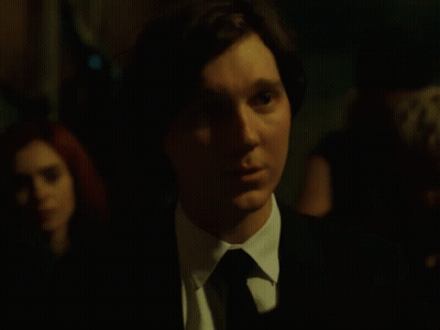 A Man In A Suit And Tie Is Looking At Something GIF