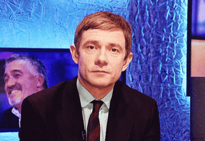 A Man In A Suit And Tie Is Looking At The Camera GIF